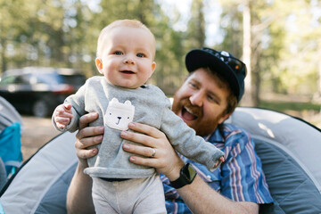 Smiling man holding baby son (6-11 months) on camping, Wasatch-Cache National Forest