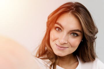 Naklejka premium Close-up of a beautiful and trendy woman is making selfie photo on white background