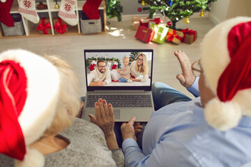 Grandparents in Santa caps video calling their family to see little grandson on Christmas Day - obrazy, fototapety, plakaty