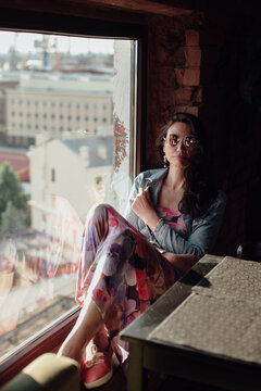 A beautiful middle-aged woman is sitting by the window.