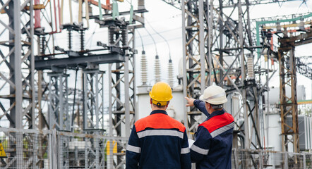 Two specialist electrical substation engineers inspect modern high-voltage equipment. Energy....