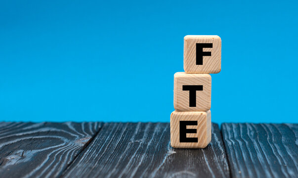 concept word FTE on wooden cubes on a blue background