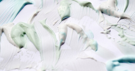 Obraz na płótnie Canvas Smears of paste green, blue and white on a white background. The concept of freshness, oral hygiene, teeth cleaning. Abstract background