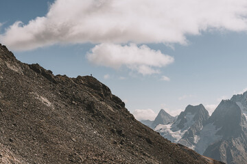 Hiking in mountain. Photo of small unrecognizable man and high-up mount peak in background. Eco...