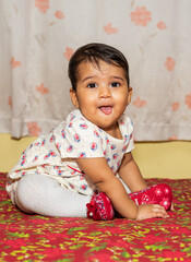 Playful Pretty Indian girl child/infant with head gear playing on the bed and giving joyful expressions