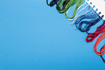 Obraz na płótnie Canvas Multicolored threads for embroidery floss on a blue background