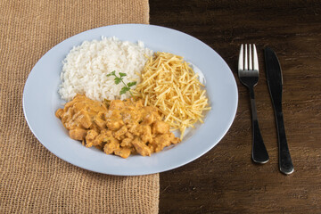 Food dish with chicken stroganoff and rice and chips.