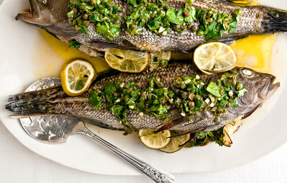 Close Up Of Whole Roasted Fish With Lime Salsa Verde Served On Plate