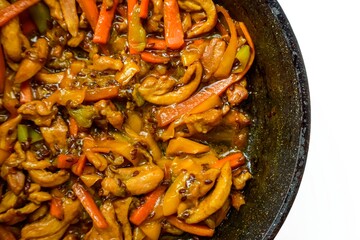 Chinese cuisine. Chicken in sweet and sour sauce with pepper in a frying pan on a white background. The kitchen of the world.