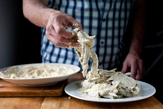 Midsection of man holding crab with cornmeal coating