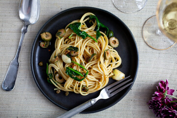 Overhead view of pasta with green puttanesca served with wine on table