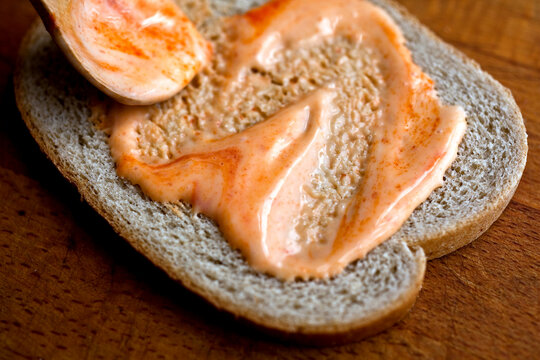 Close up of maple mayonnaise with sriracha sauce spreading on bread