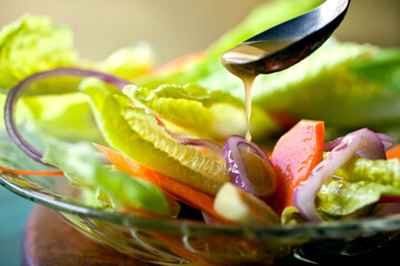Close up of mustard vinaigrette pouring over salad served on plate