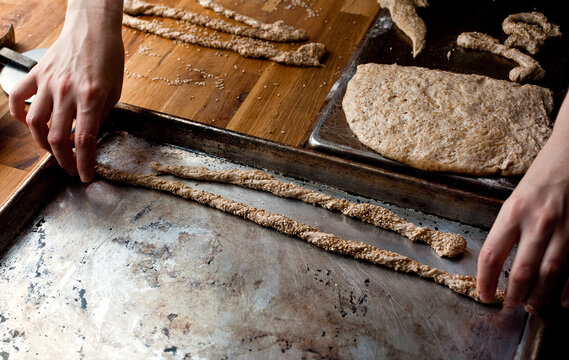 High angle view of man preparing whole wheat sesame breadsticks