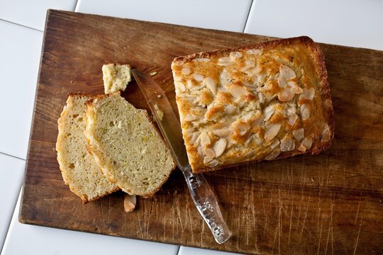 Overhead view of coconut oil pound cake with almonds and lime zest on cutting board