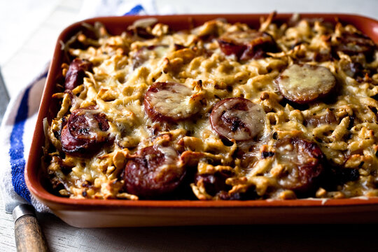 Close up of spaetzle with smoked kielbasa and caramelized onions served in tray