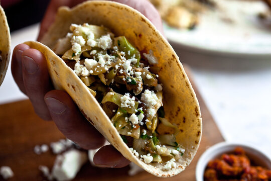 Close up of man holding tacos with mushrooms, cabbage and chipotle ranchera salsa