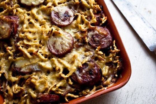Overhead view of spaetzle with smoked kielbasa and caramelized onions served in tray