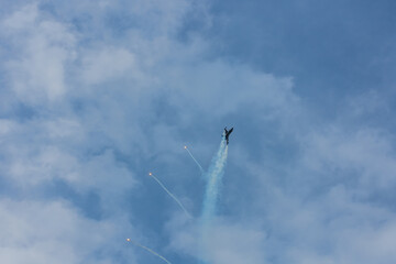 Fototapeta premium fighter plane flies up steeply at a air show with blue sky and clouds
