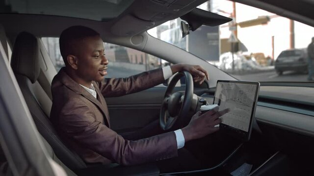 Portrait of a winner of African-American men.Happy african businessman celebrating success at luxury car.man turns on the radio in an electric car