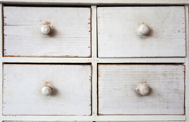 Furniture detail shot of vintage old white wooden chest of drawers background texture