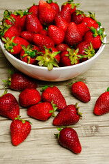 Frutillas en pocillo y esparcidas en la mesa 