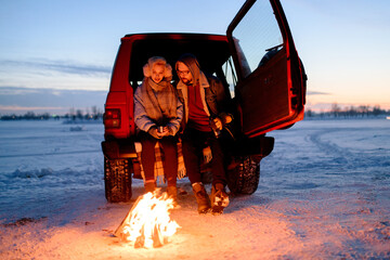 Young couple resting near campfire
