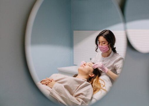 Beautician at mask working with real woman client