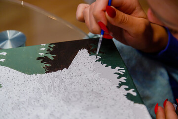 Picture by numbers. Drawing on canvas. Woman's hand with brush. Selective focus. Close up.