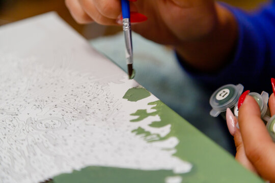 Picture by numbers. Drawing on canvas. Woman's hand with brush. Selective focus. Close up.