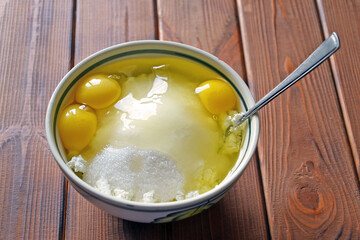 Ceramic bowl with three yolks, sugar and cottage cheese - making a pastry