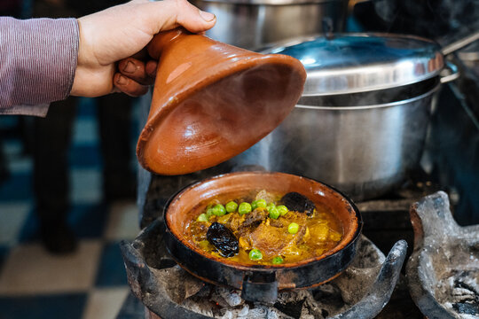 Male staff checking earthenware pot with boiling meal