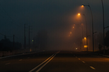 Empty dark road in foggy weather