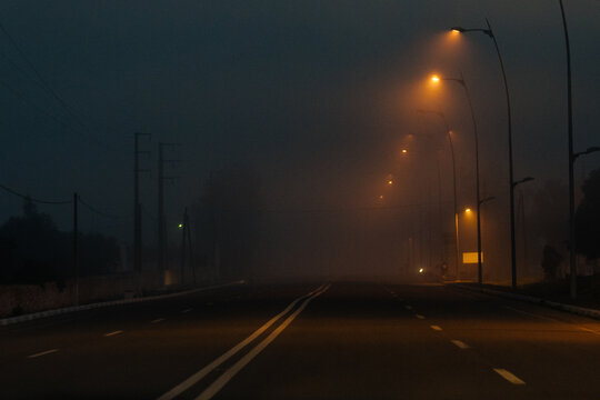 Empty dark road in foggy weather