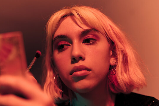 Cute young woman applying make-up