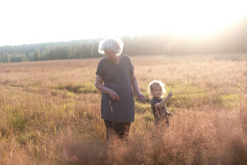 Grandmother with her grandaughter in the field on a sunset time.