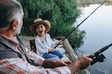 boy fishing with his grandfather by the lake