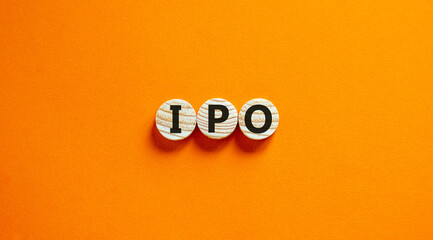 Concept word 'IPO' - 'initial public offering' on wooden circles on a beautiful orange background....