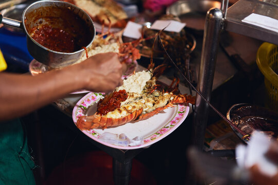 Faceless chef cooking lobster in outdoors market