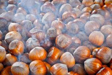 Hazelnuts on a pile close up. Texture of nuts with steam. Lots of nuts in the blue smoke.