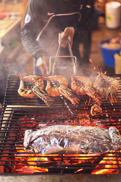 Anonymous man cooking crayfishes on grill in outdoors market