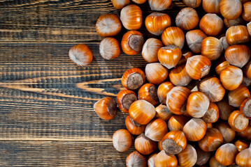 Hazelnuts on a pile close up. Texture of nuts on an old wooden board. Lots of nuts on a brown shabby table.