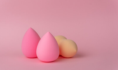 Sponges for applying makeup in the form of a drop or egg on a delicate pink background