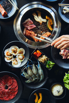 Faceless lady frying meat on grill with tongs in restaurant
