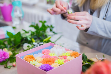 Close up view of professional woman floral artist, florist making gift box with flowers at workshop, flower shop. Floristry, holiday, birthday, handmade and small business concept