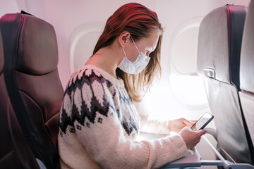 Woman sitting on a plane in a medical mask during Pandemic