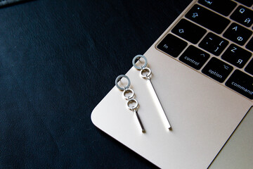 A pair of stylish earrings at laptop keyboard at dark background