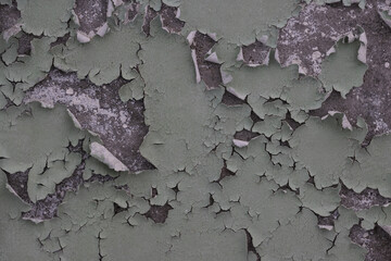 Peeling paint on the wall. Old concrete wall with cracked flaking paint. Weathered rough painted surface with patterns of cracks and peeling. Grunge texture for background and design. High resolution.