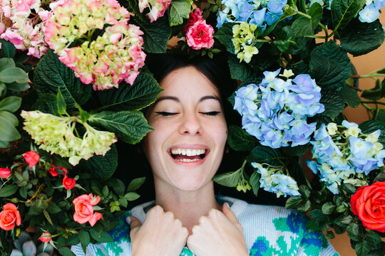 smiling woman surrounded by flowers.