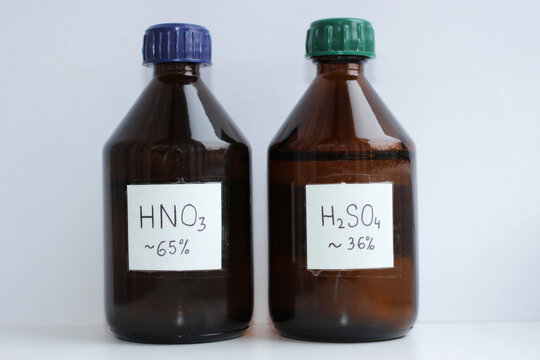 Two dark glass bottles of dilute acids, 65 percent nitric acid and about 36 percent sulfuric acid.